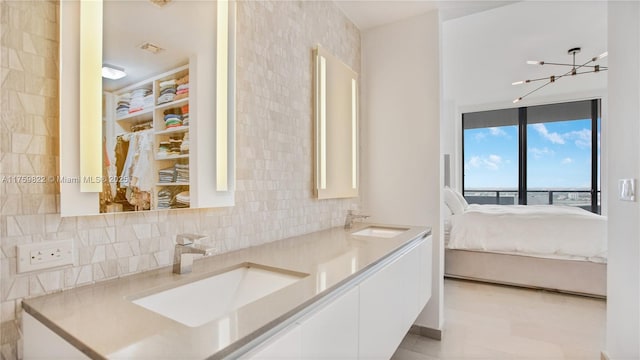 ensuite bathroom featuring double vanity, decorative backsplash, ensuite bath, and a sink