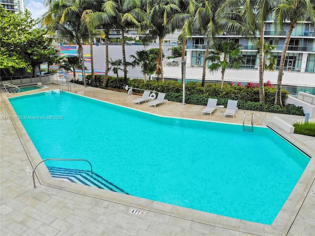 community pool with fence and a patio area