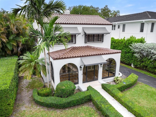 back of house featuring a tile roof, aphalt driveway, and stucco siding