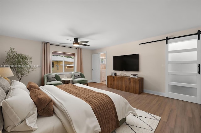 9720 Biscayne Blvd, Miami Shores, FL 33138 - bedroom featuring a barn door, wood finished floors, baseboards, a ceiling fan, and ensuite bath