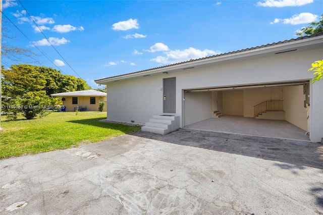 9720 Biscayne Blvd, Miami Shores, FL 33138 - rear view of house featuring driveway, stucco siding, a yard, and entry steps