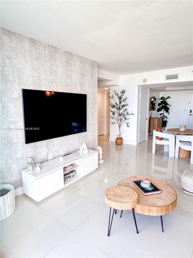 living area with tile patterned floors, visible vents, baseboards, and a textured ceiling