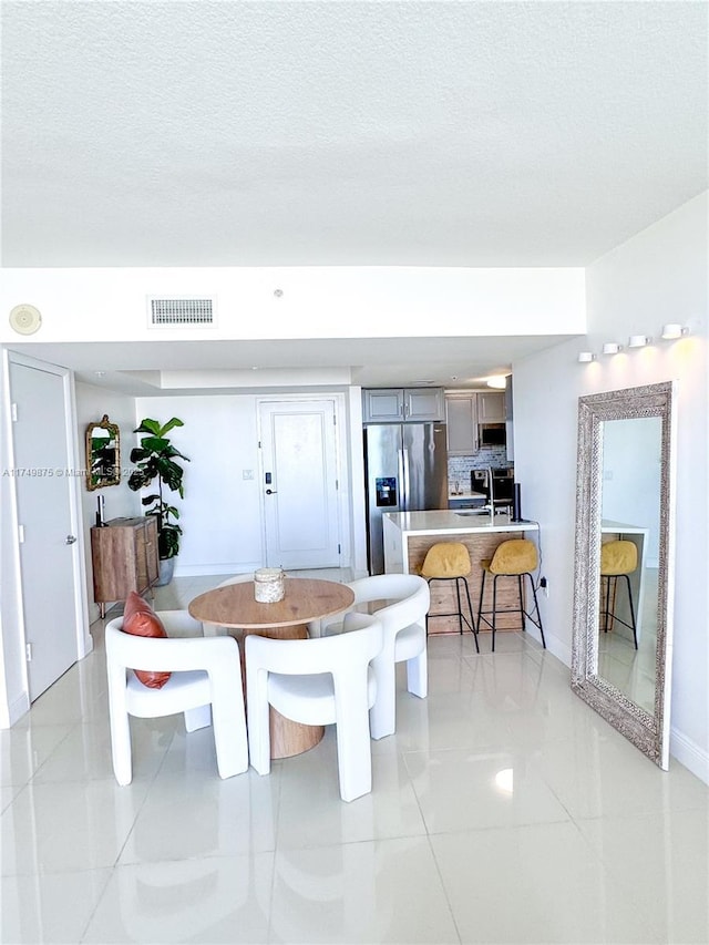 dining room featuring light tile patterned flooring, baseboards, visible vents, and a textured ceiling