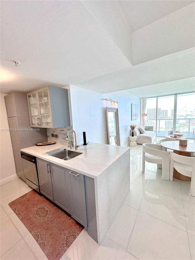 kitchen with backsplash, glass insert cabinets, dishwasher, gray cabinets, and a sink