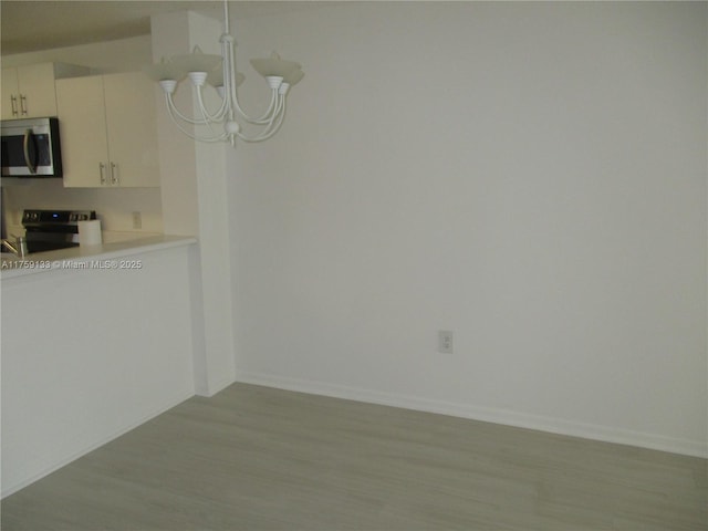 unfurnished dining area featuring baseboards, wood finished floors, and a chandelier