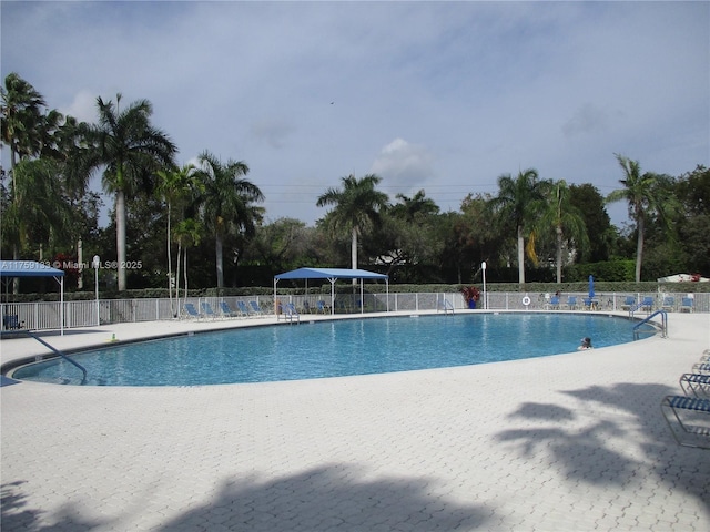 community pool with a patio area and fence