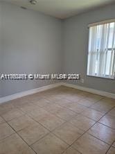 spare room featuring tile patterned floors and baseboards