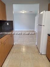 kitchen with dark countertops, light tile patterned floors, and freestanding refrigerator