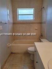 bathroom with tile patterned floors, toilet, tile walls, washtub / shower combination, and vanity