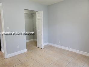 unfurnished bedroom featuring light tile patterned floors, baseboards, and a closet