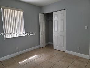 unfurnished bedroom featuring a closet, tile patterned floors, and baseboards