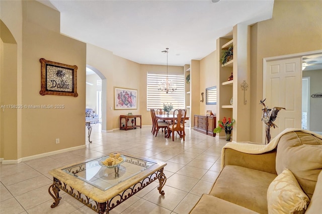 living room featuring light tile patterned floors, baseboards, arched walkways, and a notable chandelier