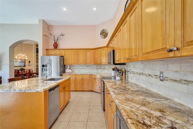 kitchen with light stone counters, light tile patterned floors, a center island with sink, a sink, and stainless steel appliances