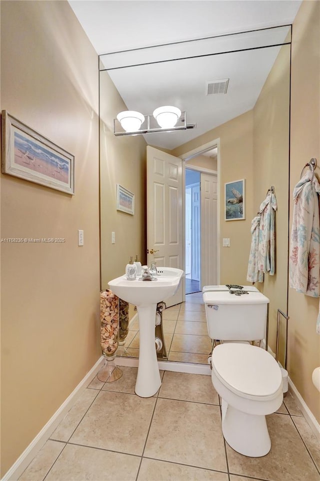 half bath with tile patterned flooring, toilet, baseboards, and visible vents