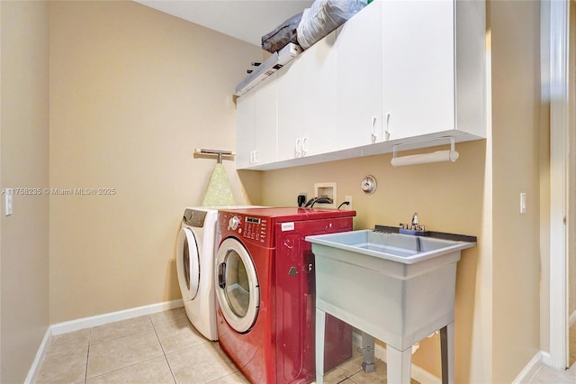 clothes washing area with light tile patterned floors, baseboards, cabinet space, a sink, and washing machine and dryer