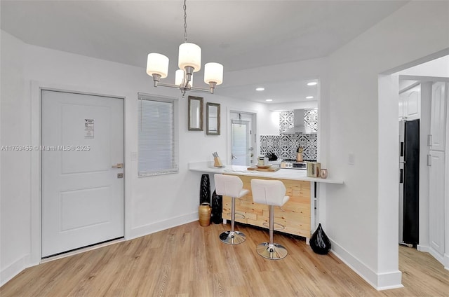 kitchen with decorative backsplash, baseboards, light wood-type flooring, and freestanding refrigerator