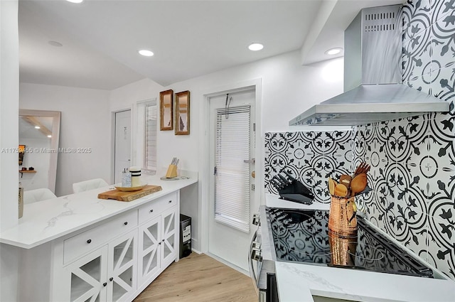 kitchen featuring light wood-type flooring, recessed lighting, island exhaust hood, stove, and white cabinets