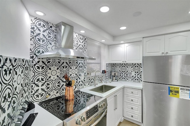 kitchen featuring a sink, appliances with stainless steel finishes, wall chimney exhaust hood, and white cabinets