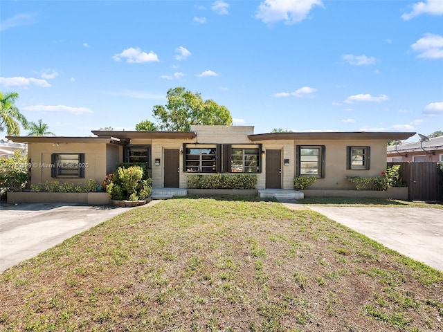 ranch-style home with a front yard, fence, and brick siding