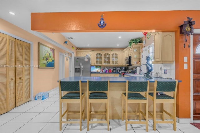 kitchen featuring a peninsula, light tile patterned flooring, stainless steel appliances, glass insert cabinets, and backsplash