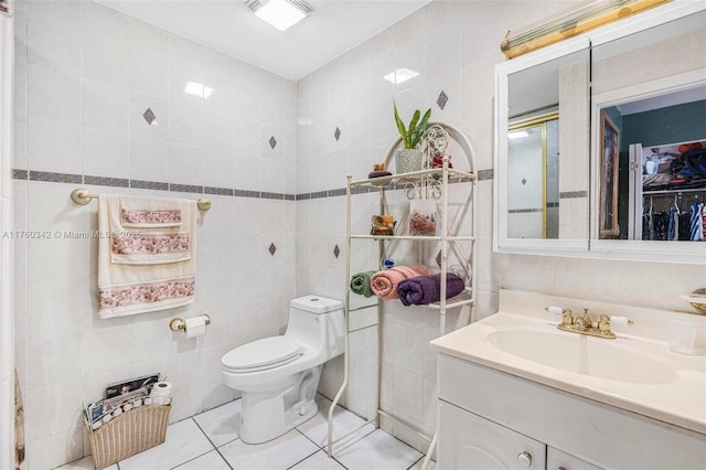 bathroom with tile patterned floors, toilet, tile walls, and vanity