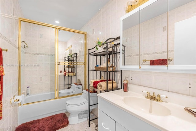 full bath featuring vanity, bath / shower combo with glass door, tile patterned flooring, tile walls, and toilet