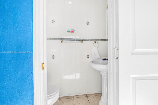 bathroom with tile patterned floors, toilet, and tile walls