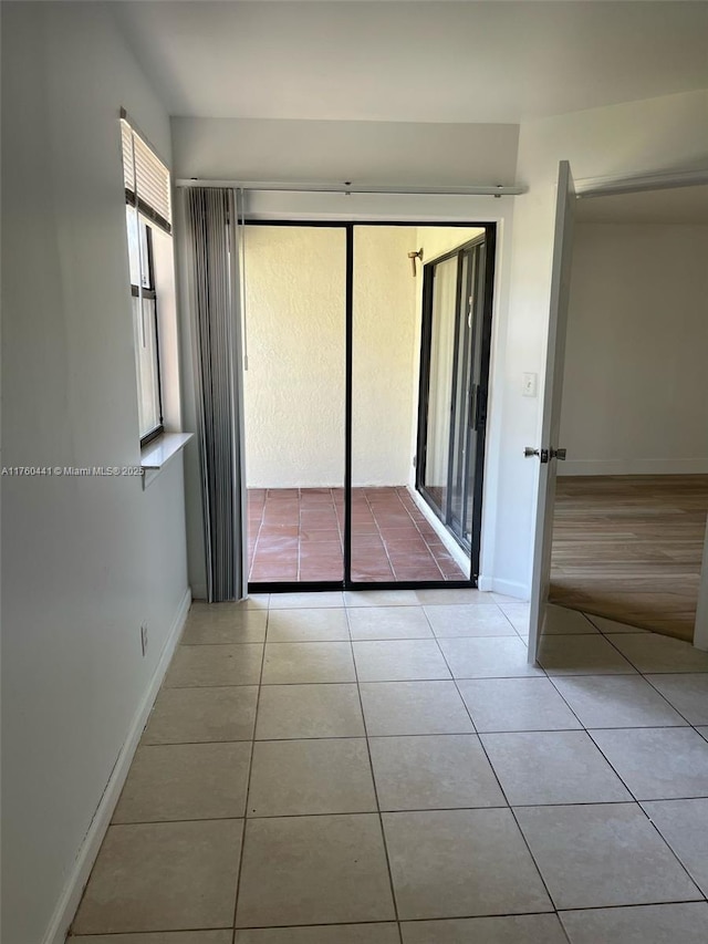 spare room featuring light tile patterned floors and baseboards