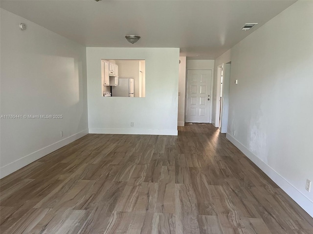 unfurnished room featuring dark wood-style floors, visible vents, and baseboards