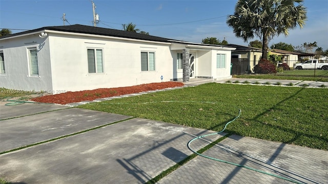 ranch-style home featuring a front lawn, fence, and stucco siding