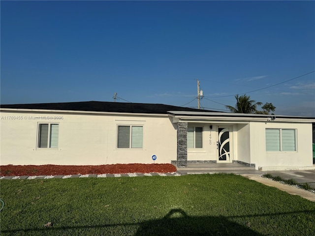 exterior space with roof mounted solar panels, stucco siding, and a front lawn