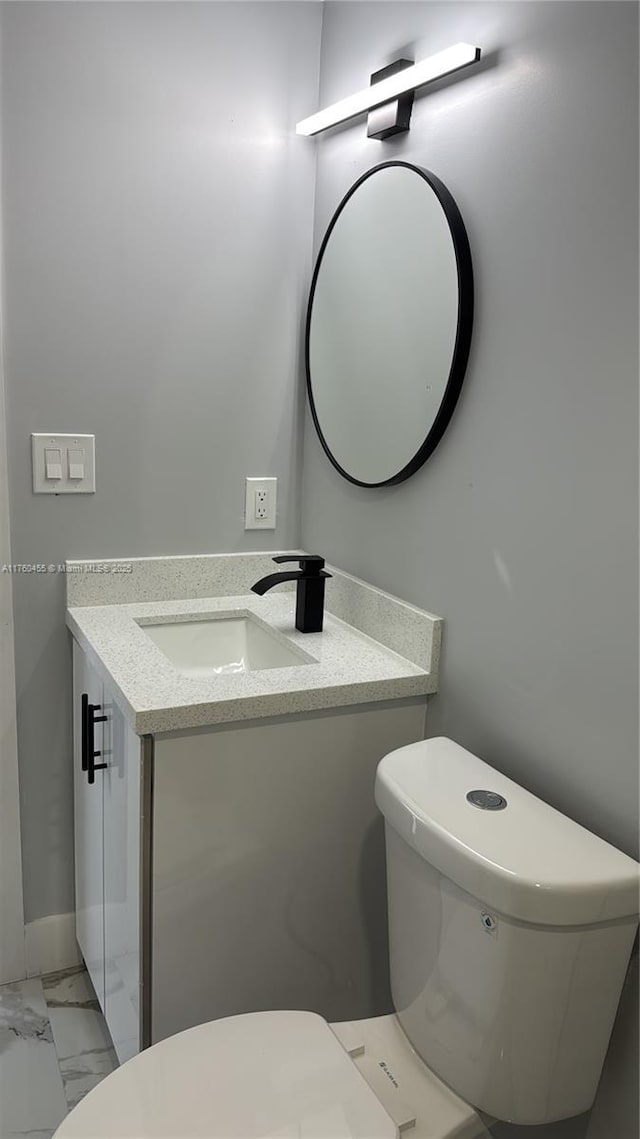 half bath featuring toilet, marble finish floor, and vanity