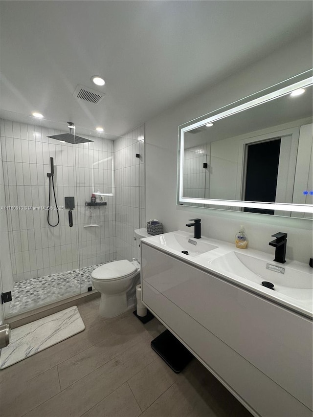 full bath featuring visible vents, a shower stall, toilet, double vanity, and a sink