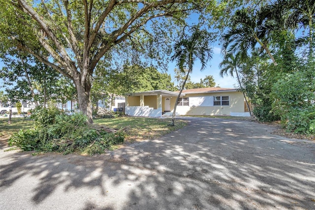 ranch-style home featuring aphalt driveway and stucco siding