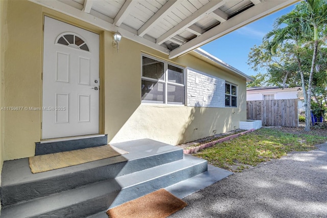 property entrance featuring fence and stucco siding