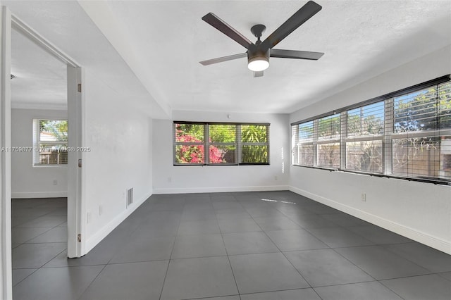 unfurnished room with plenty of natural light, a ceiling fan, baseboards, and a textured ceiling