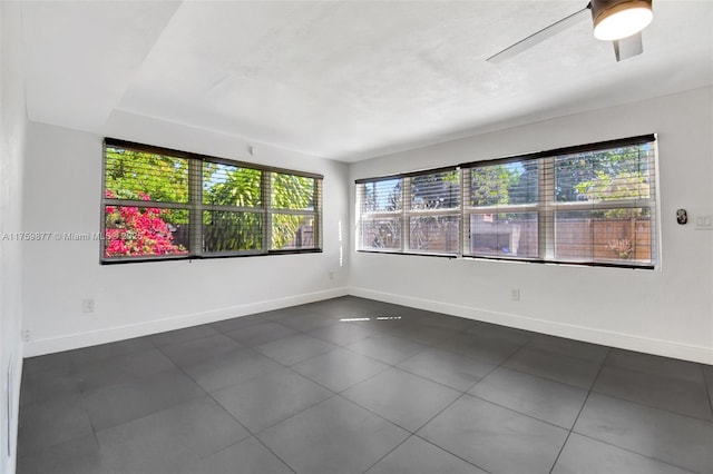 spare room with a ceiling fan and baseboards