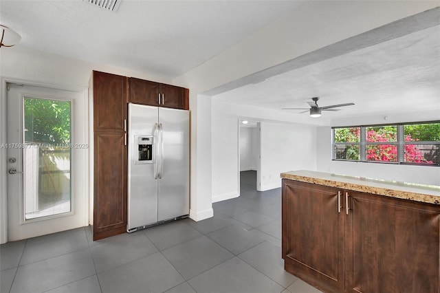 kitchen with dark tile patterned floors, a ceiling fan, stainless steel refrigerator with ice dispenser, light countertops, and baseboards