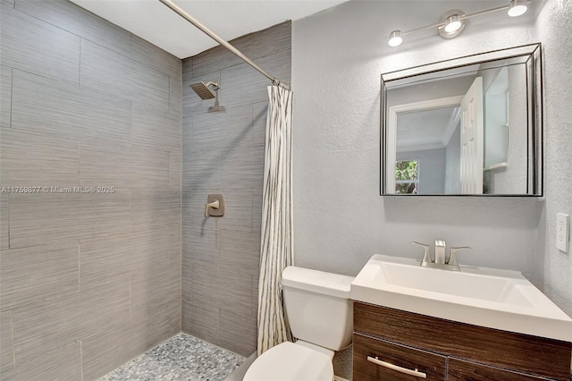 full bath featuring a textured wall, toilet, vanity, and a tile shower