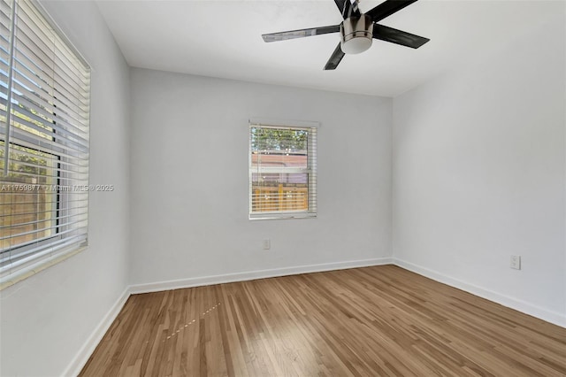 empty room featuring ceiling fan, baseboards, and wood finished floors