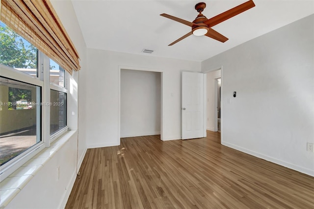 interior space featuring ceiling fan, visible vents, baseboards, and wood finished floors