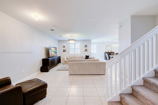 living area featuring light tile patterned flooring, visible vents, stairs, and baseboards