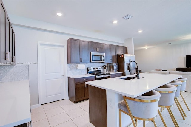 kitchen featuring light tile patterned flooring, a breakfast bar area, stainless steel appliances, and a sink