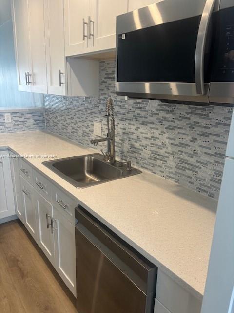 kitchen with a sink, light countertops, appliances with stainless steel finishes, and white cabinets