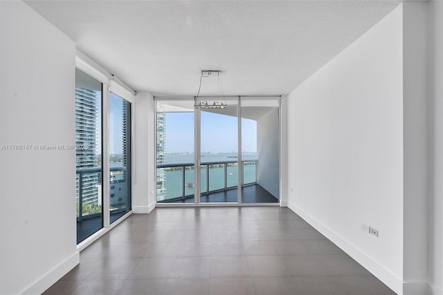 unfurnished room featuring floor to ceiling windows, baseboards, and a textured ceiling