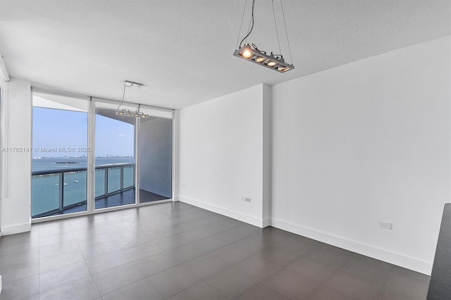 unfurnished room with expansive windows, baseboards, and a textured ceiling