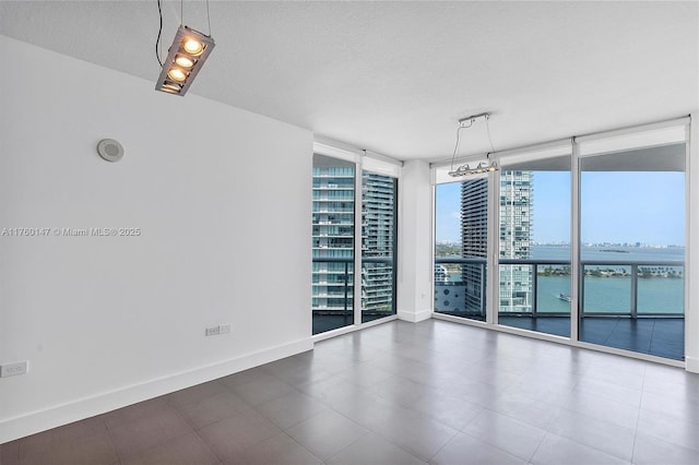 empty room with a city view, floor to ceiling windows, baseboards, and a textured ceiling