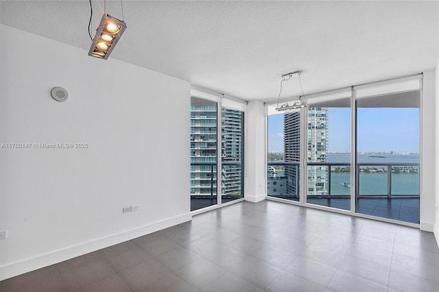 spare room with a wall of windows, a view of city, baseboards, and a textured ceiling