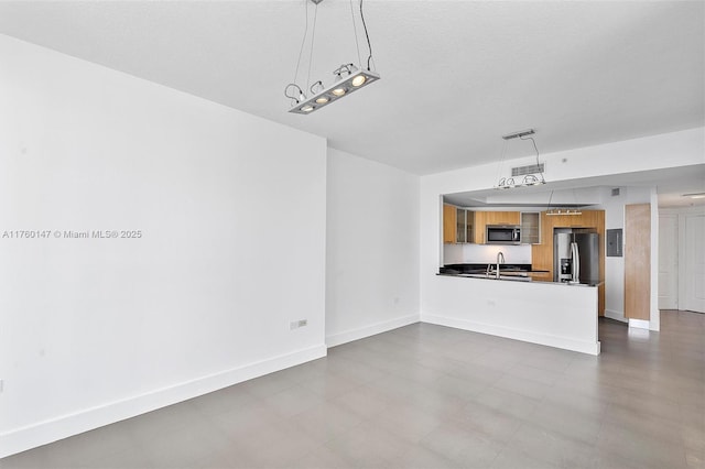 unfurnished living room featuring baseboards and a sink