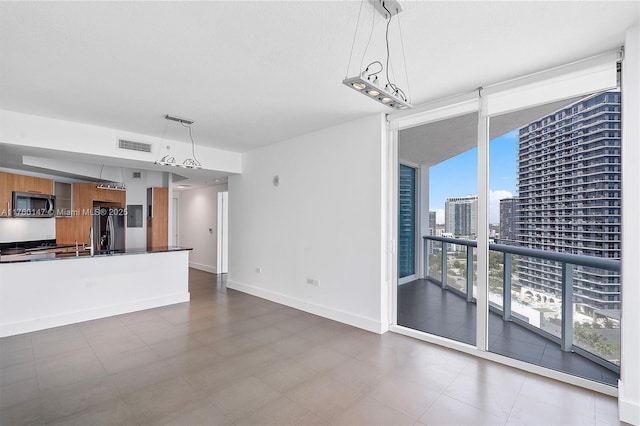 unfurnished living room with visible vents, floor to ceiling windows, a view of city, and baseboards